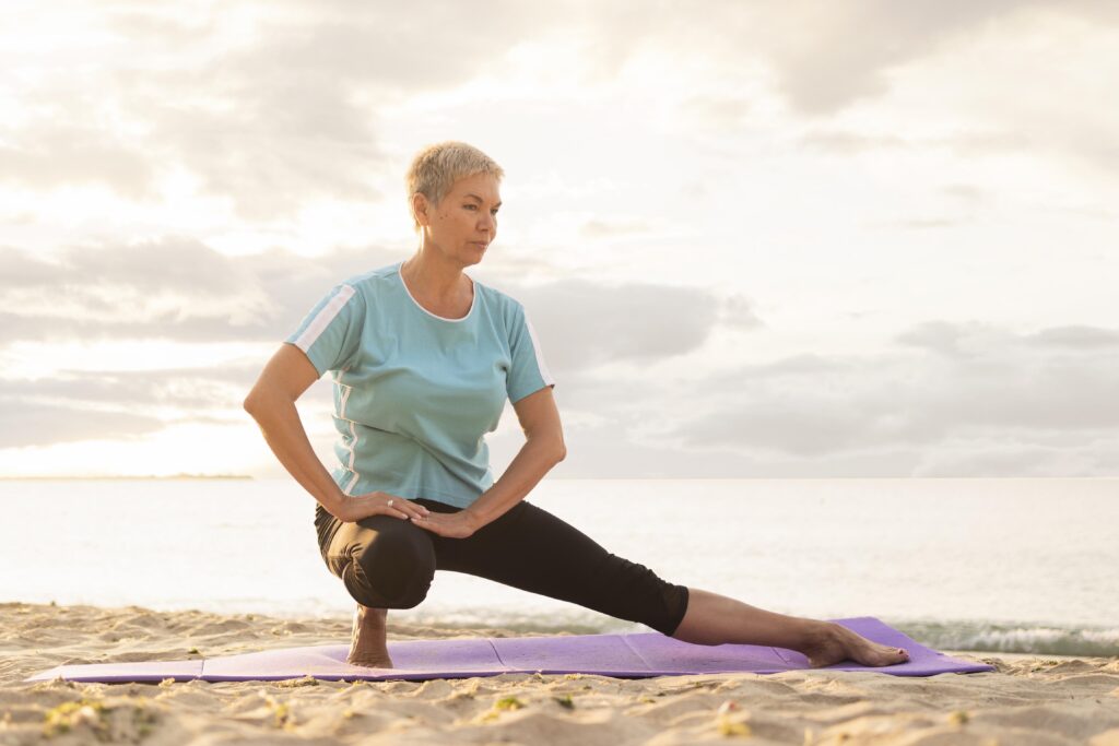 front-view-elder-woman-practicing-yoga-beach