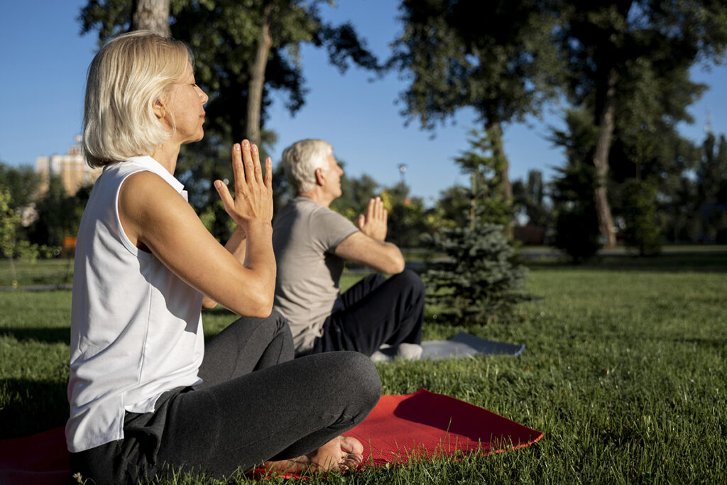 side-view-older-couple-practicing-yoga-outdoors-with-copy-space